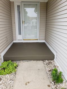 the front door of a house with gravel and plants