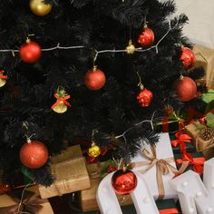 a christmas tree with presents under it and decorations on the branches next to it,