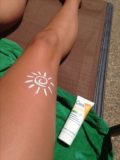 a person laying on top of a towel next to a tube of sunscreen