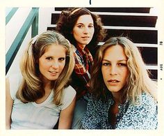 three women sitting next to each other in front of stairs