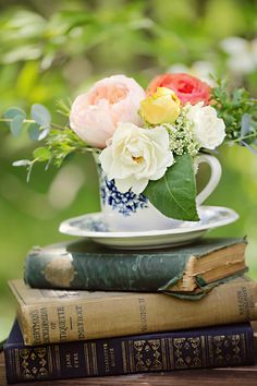 two books stacked on top of each other next to a cup with flowers in it