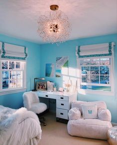 a bedroom decorated in blue and white with two chairs, a desk and a chandelier