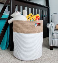 a teddy bear sitting in a toy basket next to a chair and bunk bed with a ladder