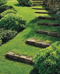 a garden with stone steps leading up to the grass