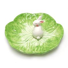 a green plate with a white bunny sitting on top of it's leafy base