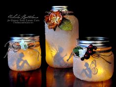 three mason jars with fairy lights in them on a dark surface, one has a flower and the other has leaves