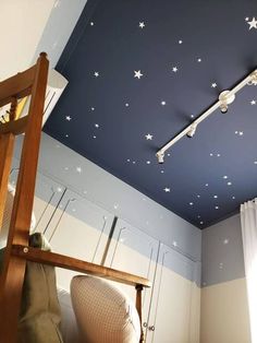 the ceiling is decorated with white stars on blue paint and wooden furniture in front of it