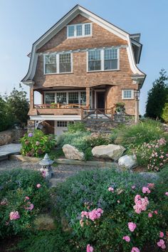 a large house with lots of flowers in front of it and landscaping on the side