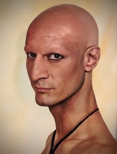 an image of a bald man with a necklace on his neck and no shirt on