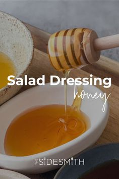 a bowl filled with honey sitting on top of a wooden table next to other bowls