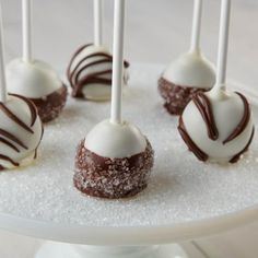 chocolate covered candies with white frosting and sprinkles on a cake plate