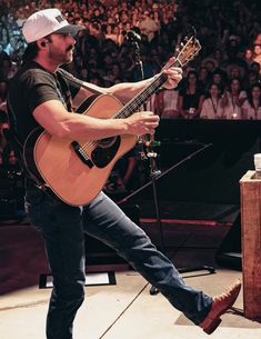 a man with a guitar on stage in front of an audience