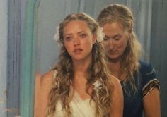 two young women standing in front of a mirror