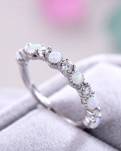 a white opal and diamond ring sitting on top of a cloth