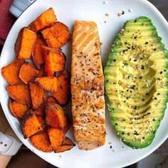 a white plate topped with salmon, avocado and sweet potatoes