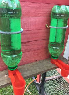 two green water bottles sitting on top of a wooden fence