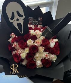 a bouquet of roses with a scary face on the top and a black box behind it