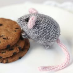 a stuffed mouse sitting next to cookies on top of a white plate with a pink string