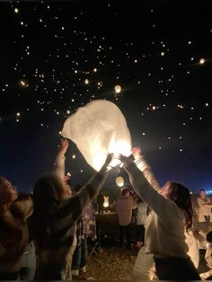 people releasing lanterns into the sky at night