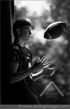 a young man holding a football in his right hand while standing next to a window