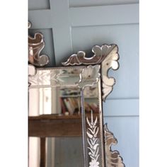 an ornate mirror hanging on the wall in front of a blue painted room with a wooden table