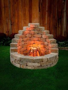 an outdoor fire pit made out of bricks and lit up with the light on it