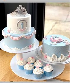 two tiered cakes with cupcakes on the side and one has a crown on top