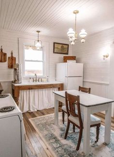 a kitchen with a table, stove and refrigerator next to a window in the wall