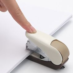 a person pushing a stapler on top of a piece of paper with their finger