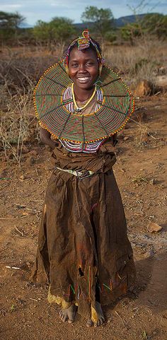 a woman with a large hat on her head in the middle of a dirt field