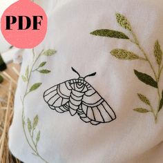 a close up of a pillow with a butterfly on it's back and green leaves