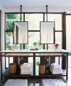 a bathroom with two sinks, mirrors and towels on the counter in front of it