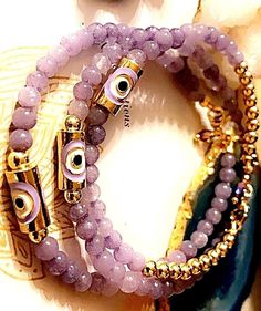 4mm Lavender purple Chalcedony dainty beads with a 24kt gold plated lavender evil eye column bead & 14kt gold plated 4mm beads & 14kt  lobster clasp components. Chalcedony lavender beads are known to have healing properties. Calming , Coping with grief, emotional balance, happiness & releases negative energy. Evil Eye protects you from those that wish bad on you or send negative energies. Natural & genuine beads . Dainty & delicate that can be worn alone or stacked.  Handmade to order with nylon Spiritual Purple Jewelry With Tiny Beads, Bohemian Gold Evil Eye Bracelet Hand-strung, Gold Beaded Amethyst Bracelets, Gold Amethyst Jewelry With 8mm Beads, Spiritual Handmade Yellow Gold Beaded Bracelets, Gold Evil Eye Bracelet With Spacer Beads, Gold Evil Eye Bracelet With Round Spacer Beads, Gold Amethyst Beaded Bracelets, Bohemian Gold Amethyst Beaded Bracelets