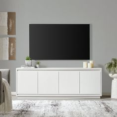 a large flat screen tv mounted to the side of a white cabinet in a living room