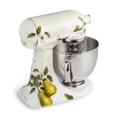 a white mixer with green leaves on the side and two pears next to it