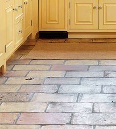 a kitchen with yellow cabinets and tile flooring