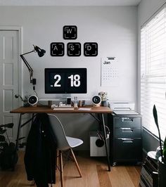 a desk with a computer on top of it in front of a wall mounted clock