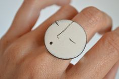 a person's hand with a ring on it that has a face drawn on it