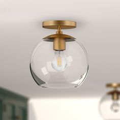 a light fixture with a clear glass ball on the bottom and a gold plated base