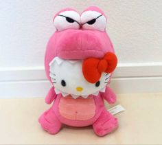 a pink hello kitty stuffed animal sitting on top of a white table next to a wall