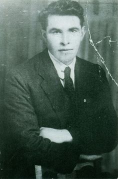 an old black and white photo of a man in a suit with his arms crossed