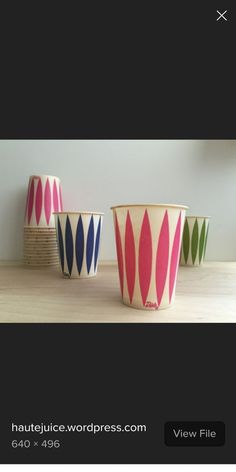 three colorful cups sitting on top of a wooden table