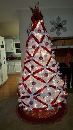 a white christmas tree decorated with red ribbon