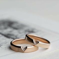 two gold wedding rings with diamonds on them sitting on top of a piece of paper