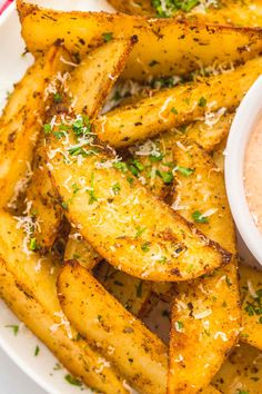 french fries on a plate with dip and parmesan sprinkles next to it