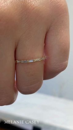 A woman's hand wearing a dainty diamond band. Stone Band Rings, Hidden Diamond Wedding Band, Aquamarine Jewelry Rings, Dainty 3 Stone Engagement Ring, White Saphire Engament Ring, Spaced Diamond Wedding Band, Simple White Gold Wedding Band, Mixed Metal Wedding Stack, Baguette Diamond Jewelry