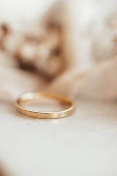 a gold wedding band sitting on top of a bed