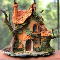 a small house made out of clay sitting on top of a table next to a tree