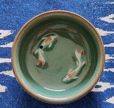 two fish in a bowl on a blue and white rug