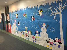 a bulletin board with snowmen, penguins and trees on it in an office hallway